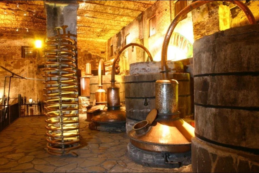 Traditional copper stills and wooden fermentation vats in a historic Jalisco tequila distillery